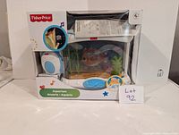Fisher-Price toy aquarium in original packaging seen from front with fish, plants, and control module visible. Clear view of the product and packaging details.