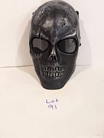 Front view of black skull mask showing mesh eye covers and detailed skull design.