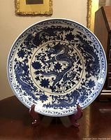 Front view of the plate on wooden stand showing blue dragon and lotus design