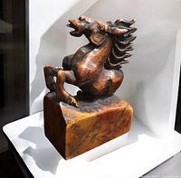 Side angle showing the detailed rearing horse carving on the stone base.