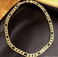 Full view of the heavy gold tone curb chain necklace laid out in a circle on a dark surface showing the link style and color.