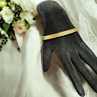 Gold over sterling silver bracelet shown on display hand form with floral background