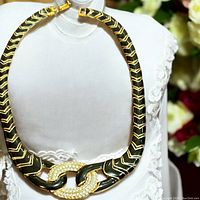 Front view of vintage Oscar De La Renta necklace on display showing black enamel and gold-tone chevron pattern with rhinestone double link center.