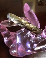 Close-up photo of the sterling silver and 14k gold mixed metal bracelet displayed on a translucent hand-shaped holder