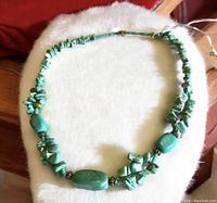 Full view of the turquoise chunky necklace laid flat on a white surface, showing the varying sizes and shapes of turquoise stones and metal spacer beads.