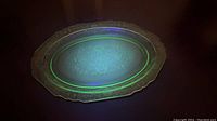 Uranium glass serving platter glowing green under UV lighting, showing the distinctive fluorescence of uranium glass.