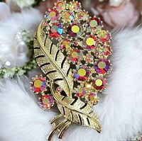 Front view of the vintage gold-tone floral brooch with multicolored aurora borealis rhinestones on a white fur background.