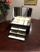 Top compartment of jewellery case open showing mirror, multiple storage compartments, and ring slots with leopard print trim around mirror.