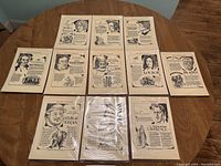 Ten assorted Minute Biographies single-page prints laid out on a wooden table, featuring historical and cultural figures.