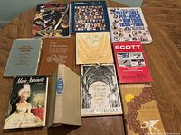 Photo showing eleven assorted old books including historical novels and collectible guides spread on a wooden table