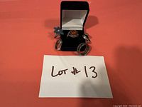 Photo showing four vintage silver rings arranged on a table with a black ring box holding one ring.