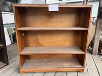 Front view of wooden book shelf with two shelves and a wood finish showing wear.