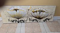 Glossy rectangular wall art showing two large white and yellow flowers with decorative swirls beneath on a crackled light background.