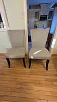 Front view of two grey fabric accent chairs side by side showing the seating area and legs.