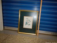 Framed floral print positioned against a blue storage unit.
