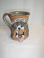 Front view of the ceramic mug showing the face design, eyes, tongue, and 'LIFE WITHOUT TEA' text