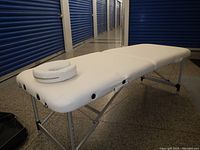 White portable massage table set up, showing the padded surface and the attached round face cradle.