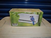 Photo of the box showing image of white plastic window bird feeder with blue jay illustration and barcode.