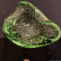 Top-down view of a Venetian glass bowl with green tint and controlled bubbles inside the glass, showing the asymmetrical flowing edges and internal bubble texture.