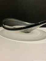 Side view of clear glass bowl showing extended upright edge and organic curved form on a white surface against a black background.