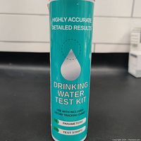 Front view of cylindrical container labeled as Drinking Water Test Kit showing 'Highly Accurate Detailed Results', '16 Parameters', and '105 Test Strips'