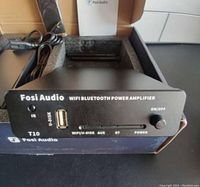 Front view of Fosi Audio T10 amplifier showing power knob, USB port, IR sensor, and input options.