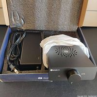 Fosi Audio amplifier and power adapter in foam-lined box.