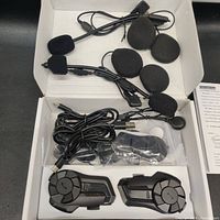 Two black two-way helmet headsets with attached microphones, foam covers, and USB charging cables in an open box.
