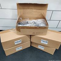 Five unopened cardboard boxes containing new black privacy door knobs; one box is open showing bubble-wrapped knobs and hardware.