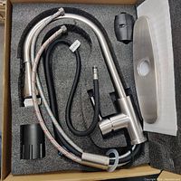 Lot contents showing faucet with hoses, mounting hardware, and cover plate in foam packaging.