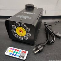 Front view of the fog machine showing circular 10-LED array with a 'Do Not Touch' warning and included wireless remote control.