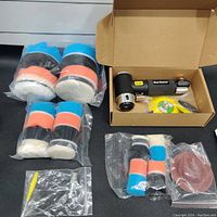 Overview of the full kit with multiple bags of polishing pads, the pneumatic sander in its box, and sanding discs