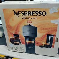 Nespresso Vertuo Next box showing branding, image of the coffee machine and cups with coffee, highlighting the espresso and coffee types available.