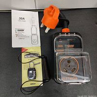 Full view of surge protector with instructions, orange power plug cap, and combination lock on black surface.