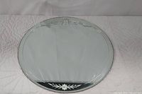 Full view of round mirror showing top and bottom etched floral design details.