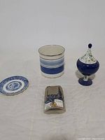 Overall lot showing metal utensil holder, Blue Willow pattern plate, lidded pedestal dish, and blue glass stones