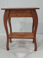 Front view of solid wood box table showing curved legs, lower shelf, and overall condition