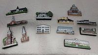 Full overview of 13 Cat's Meow wooden collectible buildings arranged on white surface, various churches and landmarks.