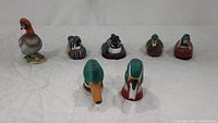 Photo shows seven duck figurines arranged in two rows, front two pieces are green-headed, likely salt and pepper shakers.