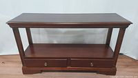Front view of dark brown solid wood console table showing two drawers and open shelf.