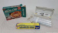 Photo showing K-tel Micro-Chip potato chip maker with original box, vacuum sealer machine, and rolls of vacuum sealer film tightly rolled and sealed with stretch-tite plastic wrap.