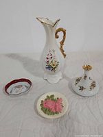 Front view of entire collection on white surface showing pitcher, vase, 40th Anniversary plate and ceramic plate.