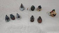 Top view of eleven miniature duck figurines arranged on a white surface showing variety in colors and styles.