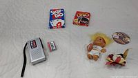 Photo showing all items in lot: Sanyo microcassette recorder with Sony microcassette tape, Skip-Bo and Uno card games, Redskins mascot doll, button pin, and small plush football item.