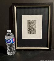Framed print of 'An Old Song' positioned next to a water bottle for scale. The frame is dark wood with a worn look.