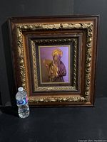 Full view of the vintage wooden frame with intricate gold decorations surrounding the staged photo of the hooded woman.