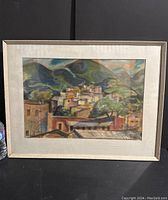 Framed watercolour painting showing the full artwork of houses and hills in earthy tones.