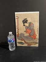 Full view of Japanese woodblock print next to water bottle for size reference