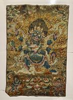 Full front view of unframed thangka textile depicting wrathful deity against flaming background.