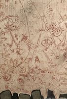 Close-up photo showing pink pencil drawings and writings including 'Russia', 'I love Canada', peace signs and smiley faces on paper.